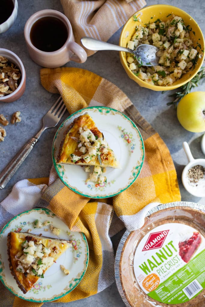 Table with two plates of Rosemary Potato Frittata with Walnut Pie Crust, coffee cups, and various ingredients.