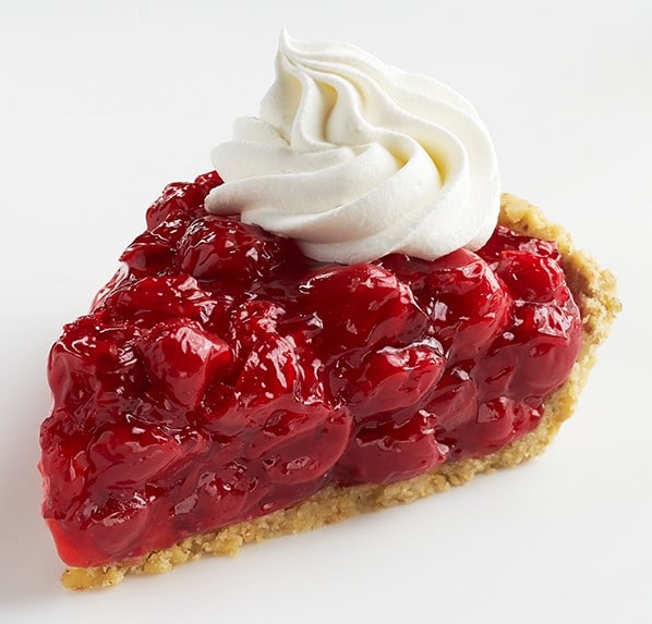 Slice of Walnut Cherry Pie topped with whipped cream.