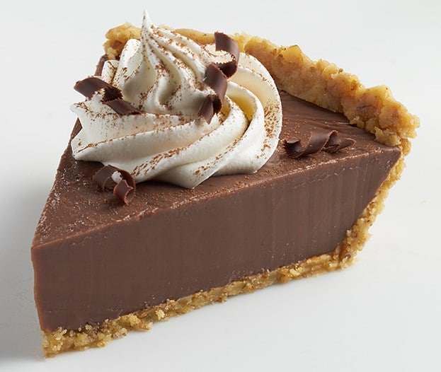 Slice of Chocolate Cream Pie with Walnut Crust, whipped cream, and chocolate curls.