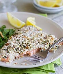 Plate with Almond Crusted Salmon, greens, and lemon slice.