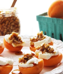 Plate of apricots topped with cream, honey, and walnuts.