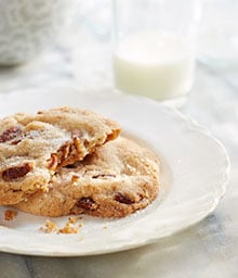 Butter Pecan Cookies with bite taken out and glass of milk.