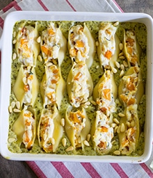 Casserole dish of Butternut Squash Jumbo Shells with Pesto Cream Sauce topped with pine nuts.