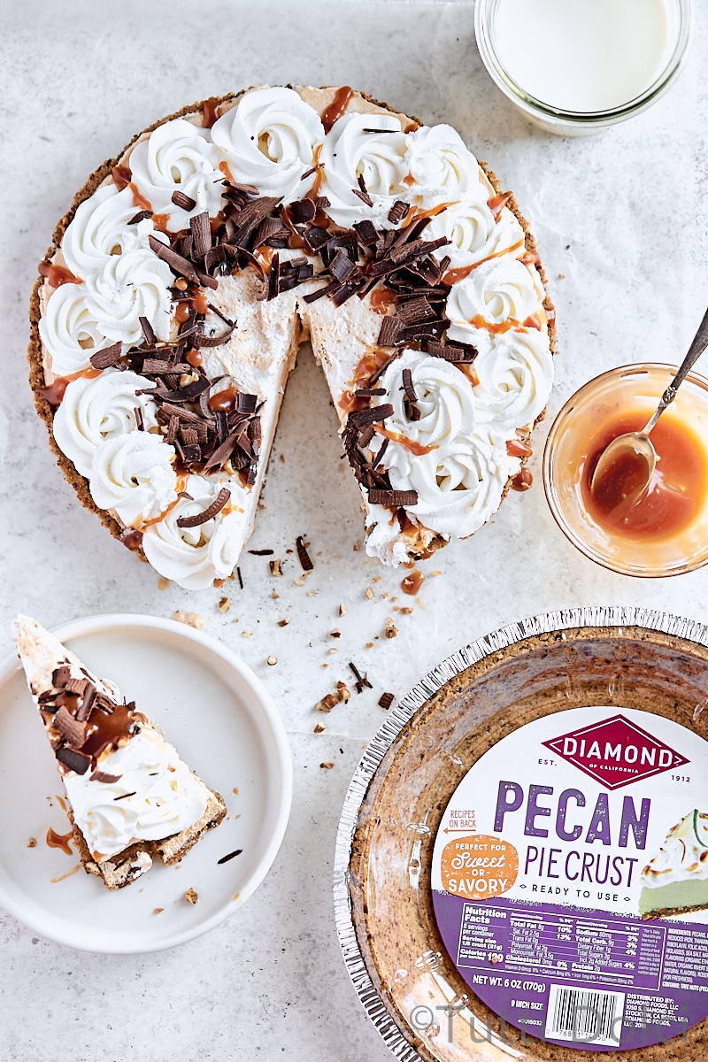 Caramel Pecan Turtle Pie topped with whipped cream and chocolate pieces.