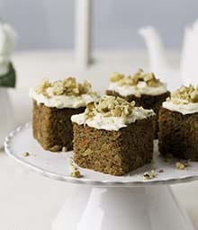 Raised cake platter with four slices of Carrot Walnut Cake.