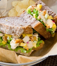 Curried Mango Walnut Sandwich cut in half next to potato chips.