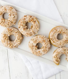 Half dozen Pumpkin Donuts, one with bite taken out.