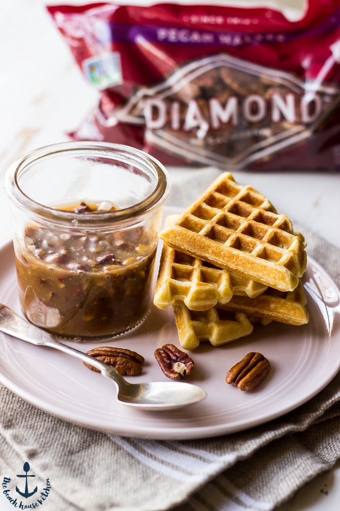 Plate of Easy Pecan Waffles and cup of Pecan Praline Sauce.