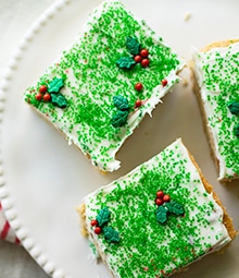 Frosted Walnut Sugar Cookie Bars with green sprinkles and holly decorations.