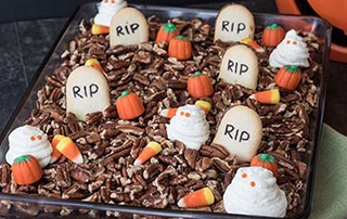 Pecan Graveyard Cake with gravestone, pumpkin, and ghost decorations.