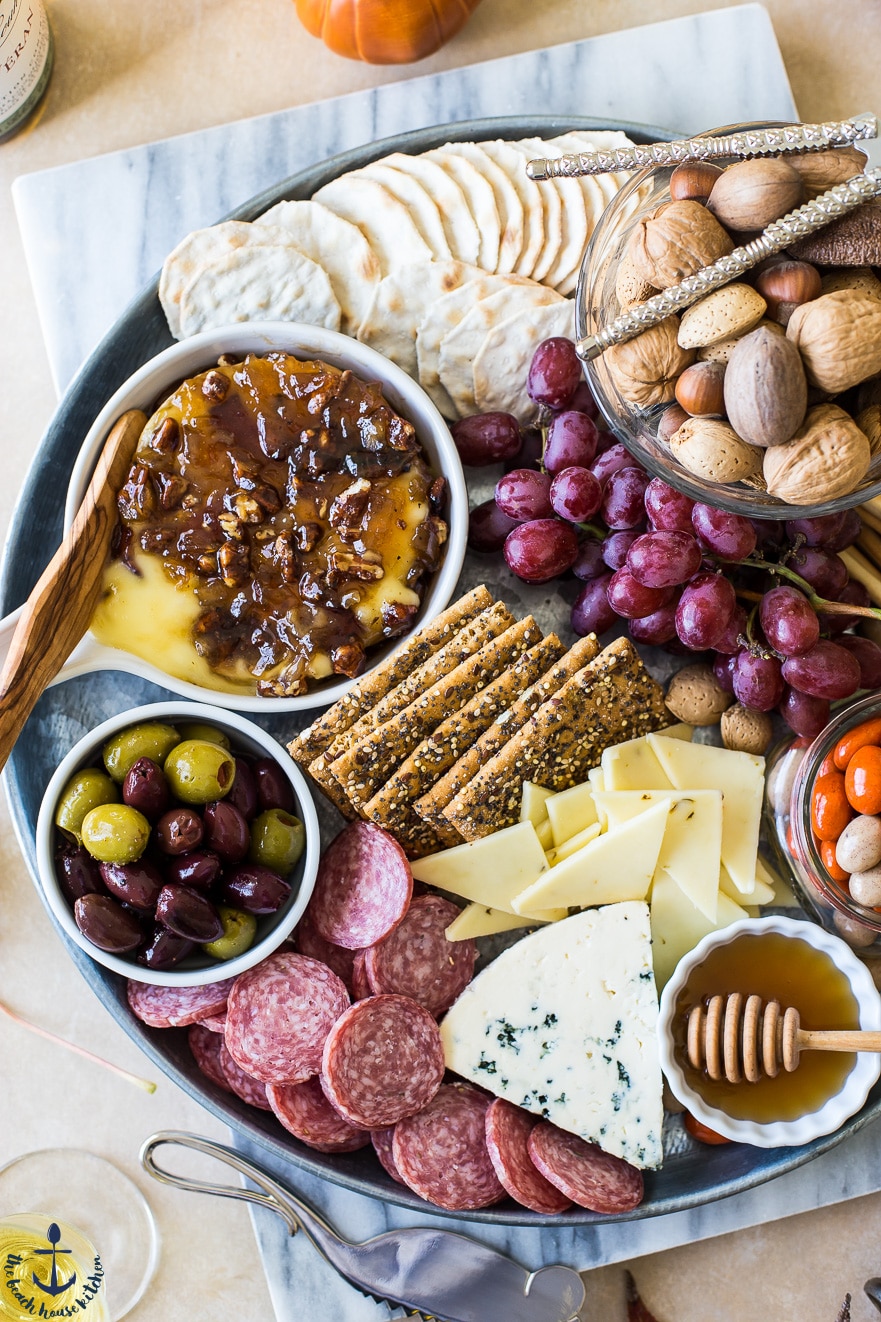 Holiday Cheeseboard with Baked Brie with Bacon Onion Jam, Glazed Pecans, and other snacks.