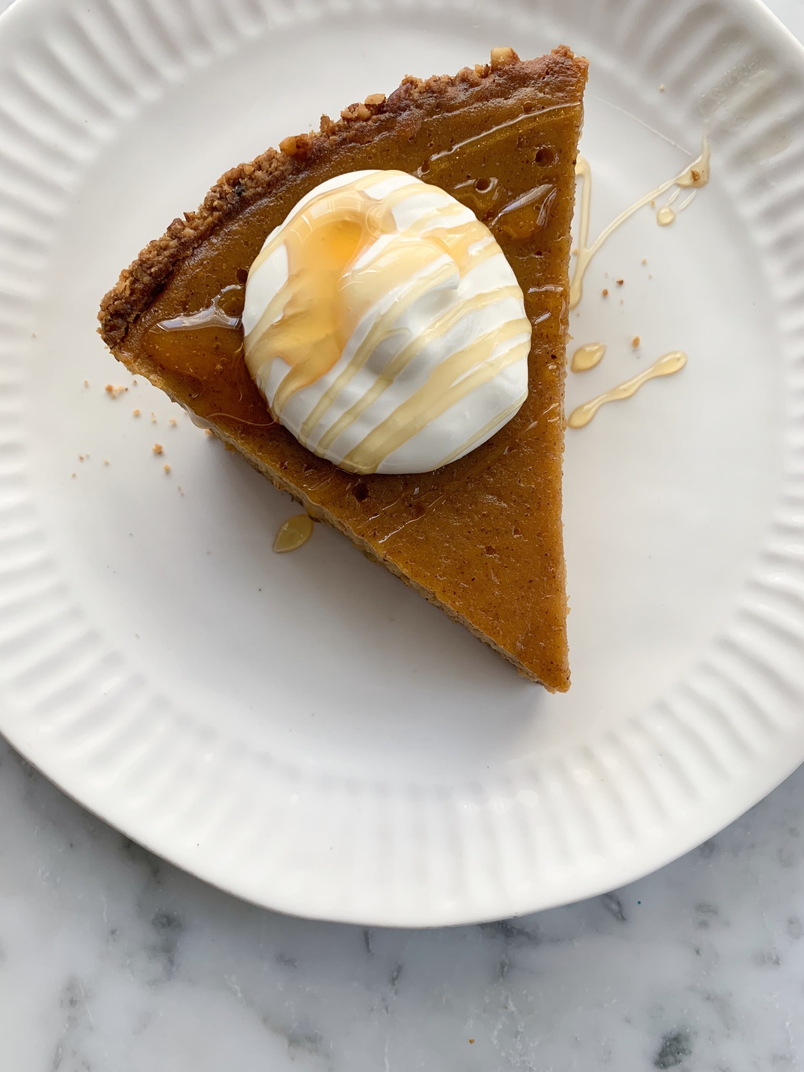 Slice of Honey Butternut Pie with whipped cream and drizzled honey.