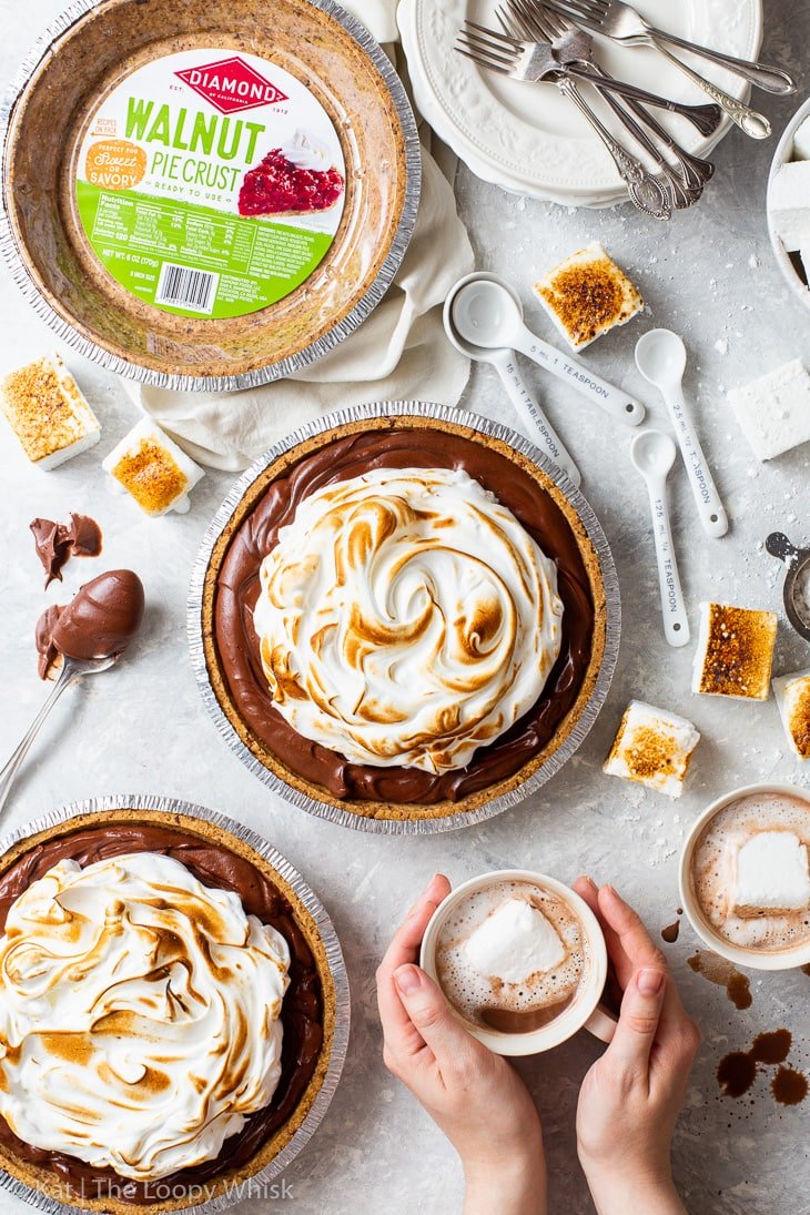 Hot Chocolate Pie next to Diamond Walnut Pie Crust and person holding mug of cocoa.