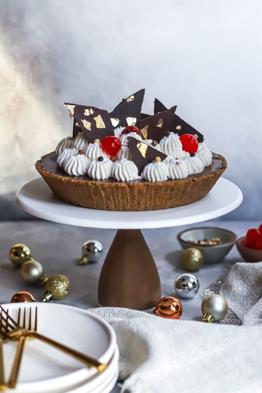 Festive Black Forest Pie with Pecan Crust topped with whipped cream, cherries, and chocolate shards.