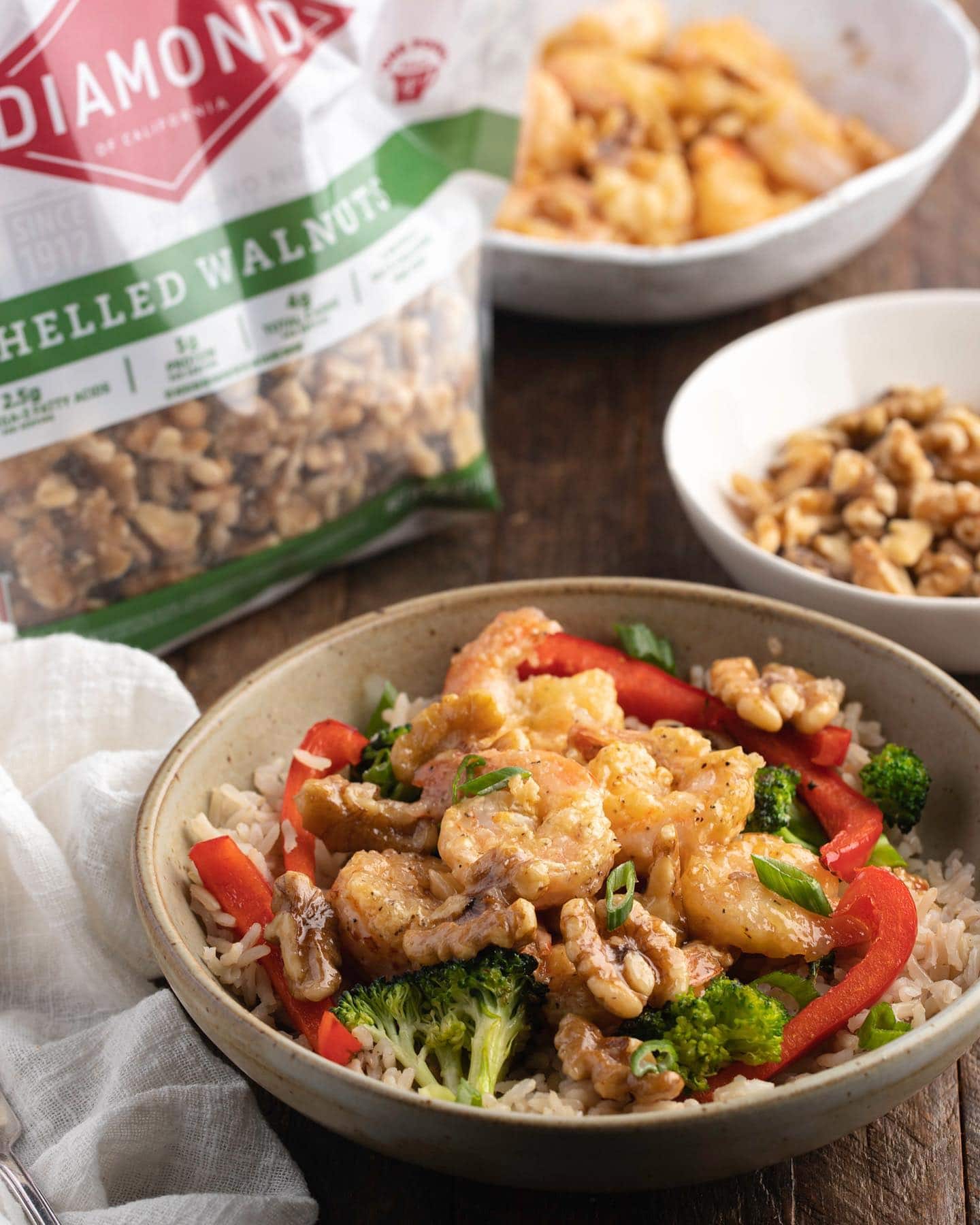 Bowl of rice, veggies, and honey walnut shrimp next to bag of Diamond shelled walnuts.