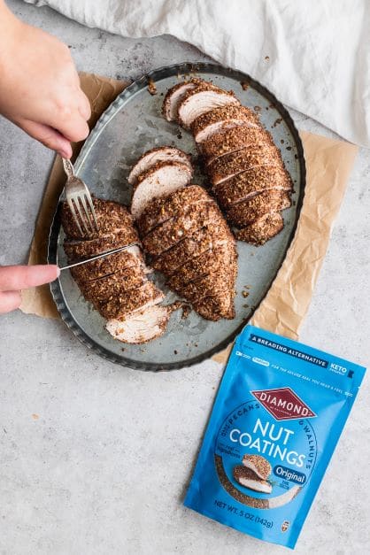 Person slicing Nut-Coated Chicken Breast next to bag of Original Diamond Nut Coatings.