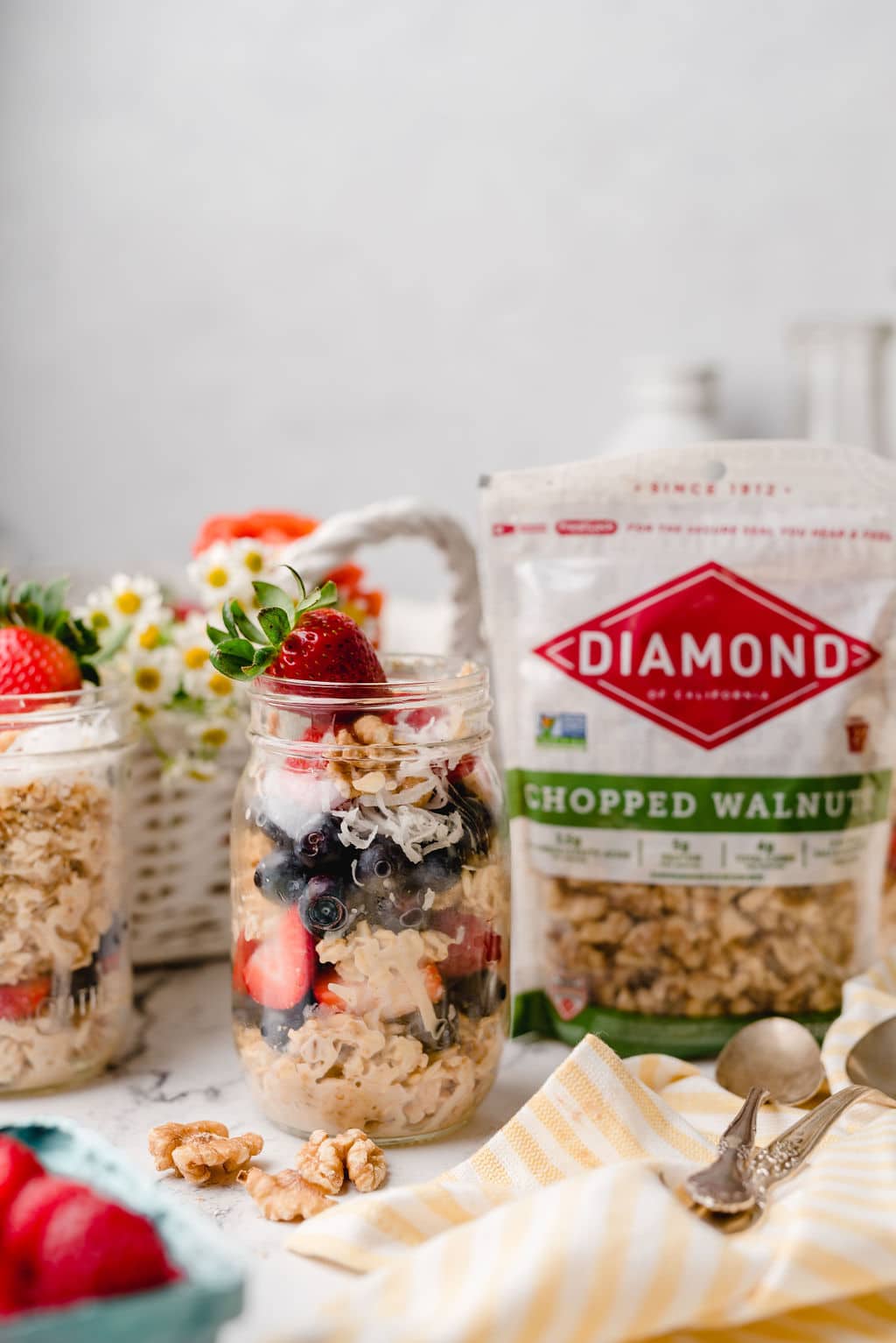 Mason jars filled with Walnut Berry Overnight Oats next to bag of Diamond chopped walnuts.