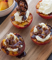 Person making Grilled Peaches with Mascarpone and Caramelized Pecans.