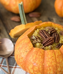 Pumpkin Pie Oatmeal in a small hollowed pumpkin topped with pecans.