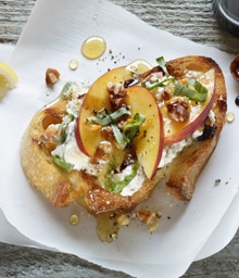 Slice of Ricotta Walnut Bruschetta topped with apples and honey.