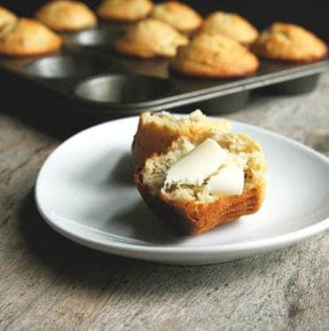 Plate with Sarah's Cucina Bella Banana Pistachio Muffin sliced topped with butter.