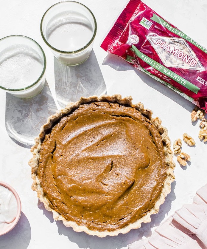 Top view Vegan Walnut Pumpkin Pie next to bag of Diamond shelled walnuts.