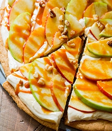 Triangular slice being cut from Apple Dessert Pizza with Caramel Cream Cheese Frosting.
