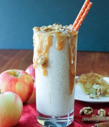 Glass with an Apple Pie Milkshake overflowing with caramel sauce.