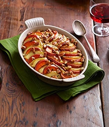 Casserole dish of Yams Baked with Apples and glass of wine.