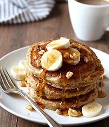 Stack of Whole Wheat Banana Nut Pancakes drizzled with syrup.