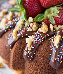 Banana Split Bundt Cake with dripping chocolate, strawberries, and walnuts.