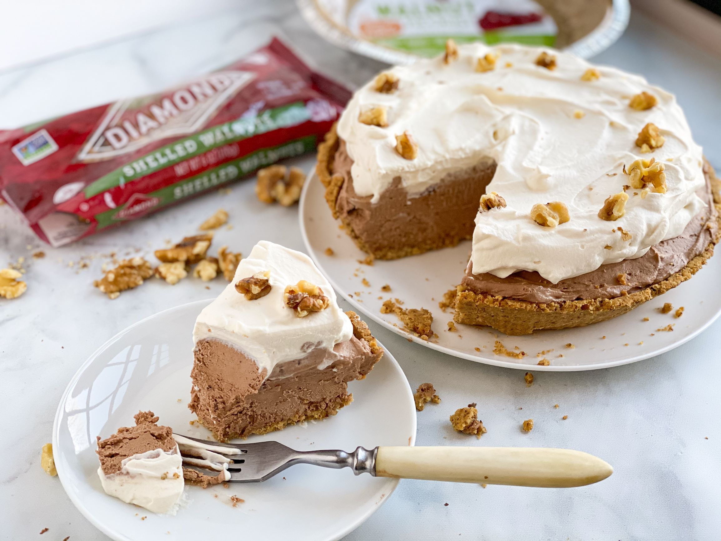 One slice taken out of Frozen Swiss Chocolate Pie next to bag of shelled walnuts.