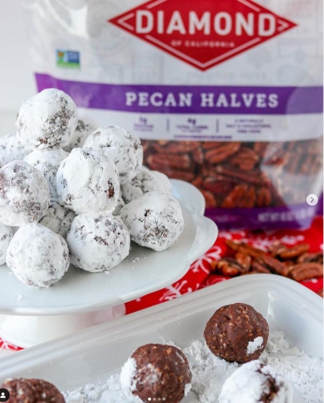 No-Bake Chocolate Bourbon Balls coated in powdered sugar in front of bag of Diamond pecan halves.