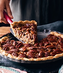 Person taking slice of Pecan Pie.