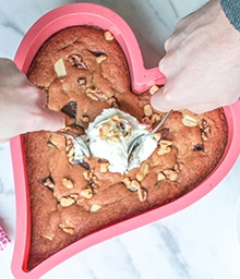A couple digging into heart-shaped Walnut Triple Chocolate Cookie Cake.