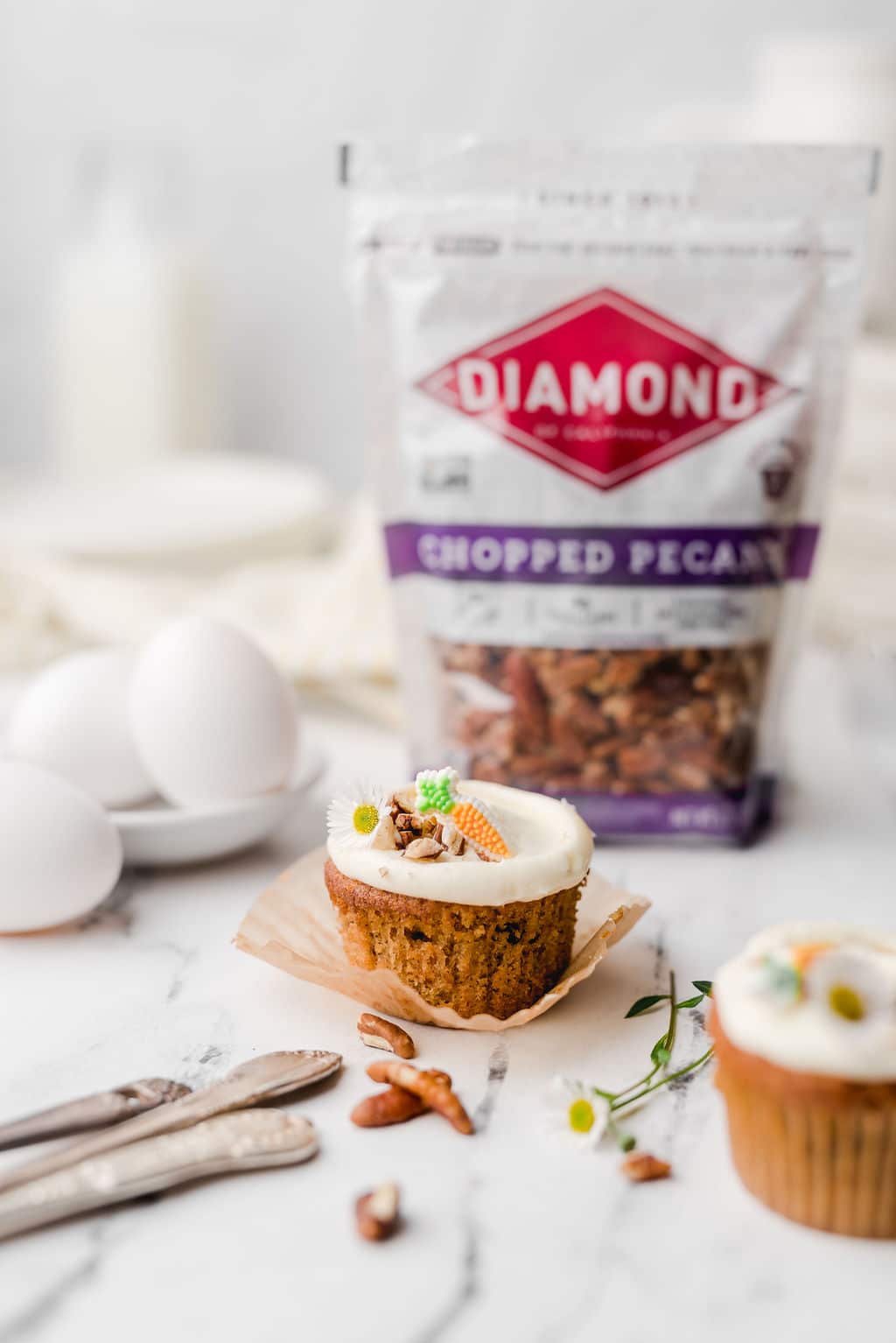 Decorated carrot cupcakes in front of bag of Diamond chopped pecans.