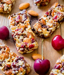 Cherry Chocolate granola bars next to fresh cherries and almonds.