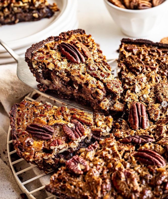 Person serving a slice of Chocolate Pecan Pie.