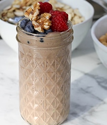 Glass cup with Chocolate Walnut Smoothie topped with berries and nuts.