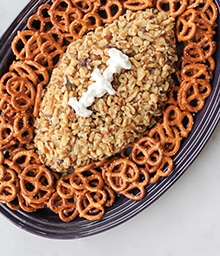 Cookie dough dip in the shape of a football surrounded by pretzels.