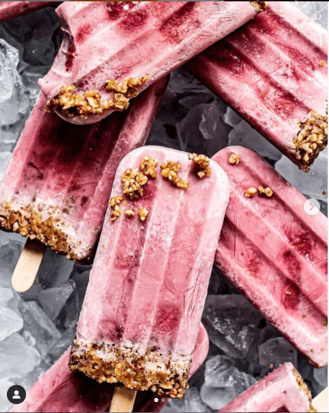 Strawberry Cream Pie Popsicles, one with a bite taken out.