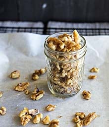 Mason jar overflowing with Whiskey Honey Toasted Walnuts.