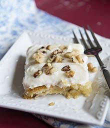 Slice of frosted White Texas Sheet Cake with chopped Diamond nuts.