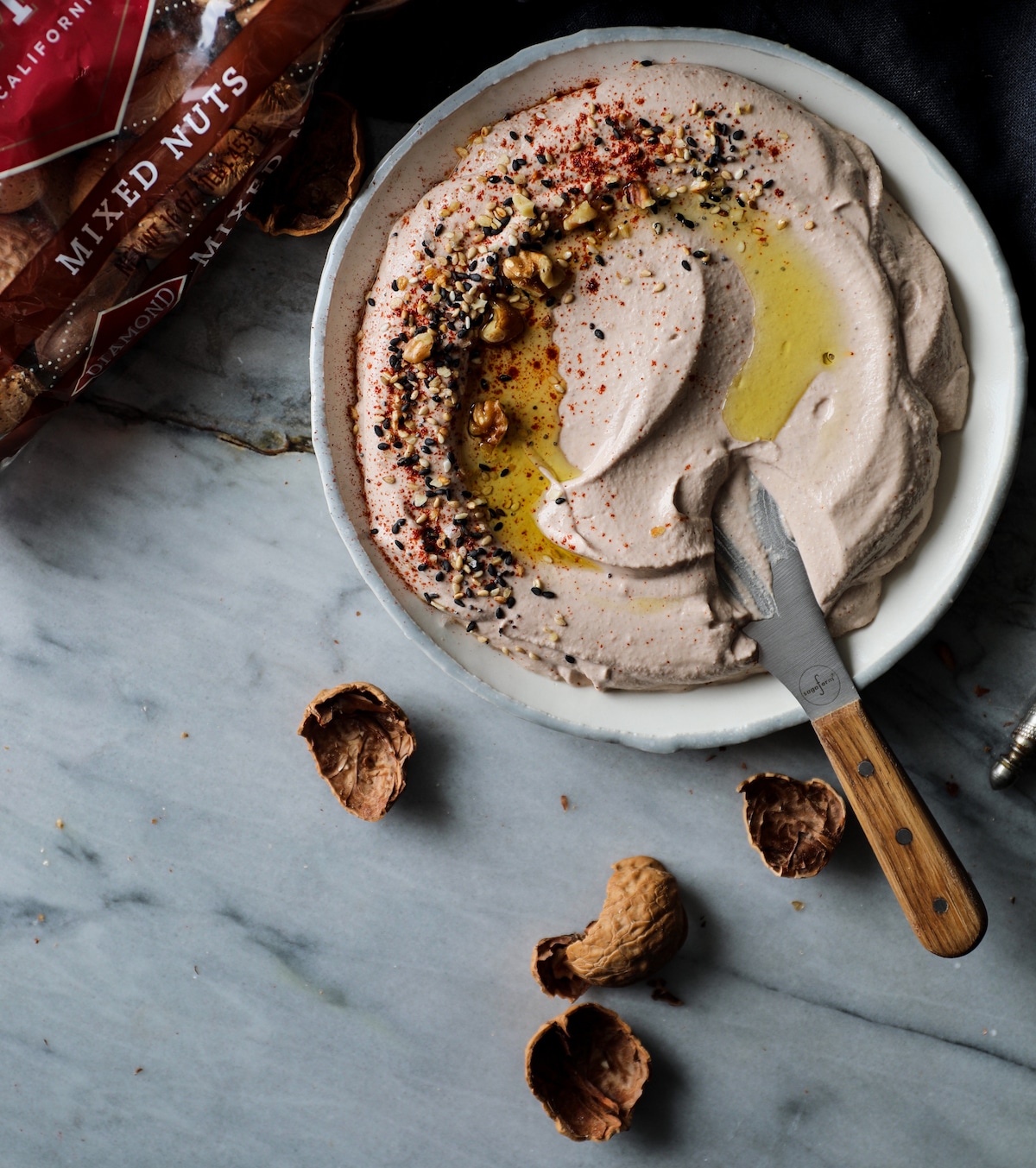 Spreader knife in bowl of Creamy Roasted Walnut Tahini Dip.