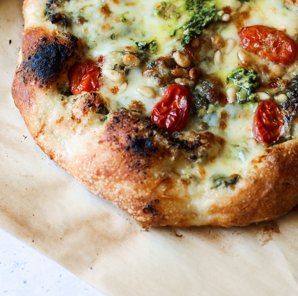 Close-up of cheesy Pesto Pine Nut Pizza.