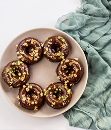 Six Chocolate Doughnuts arranged in a ring on a plate.