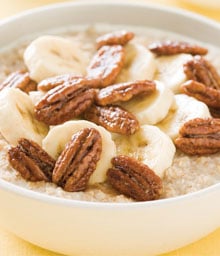 Bowl of Praline Banana Oatmeal topped with bananas and nuts.
