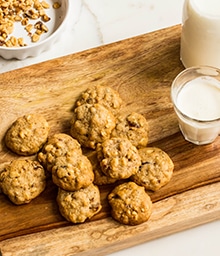 Cutting board stacked with Diamond Nuts Rock Cookies and glass of milk.