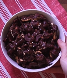 Person grabbing bowl of Chocolate Dipped Spiced Cashews.