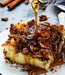 Syrup pouring on piece Overnight Cinnamon Pecan French Toast Casserole.